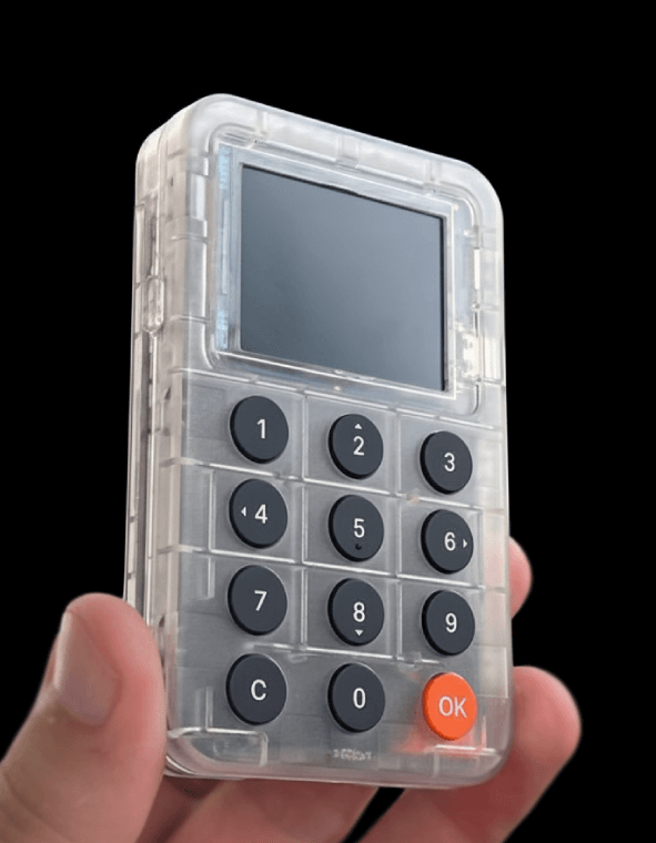 Hand holding a transparent electronic device with black buttons and an orange 'OK' button on a black background